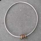 three gold beads on silver bangle